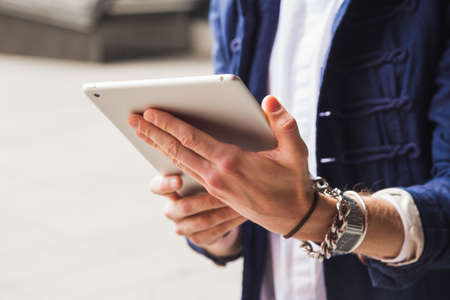 Detail of man hands with trendy clothes using a smart tabletの写真素材