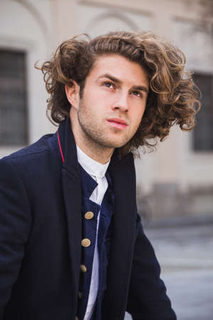 Portrait of young man with blonde curly hair and trendy clothes
