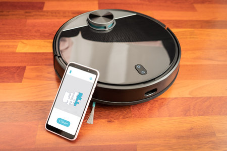Automatic vacuum cleaner robot to clean the floor and help in housework controlled by an smart phone with an app mockupの写真素材