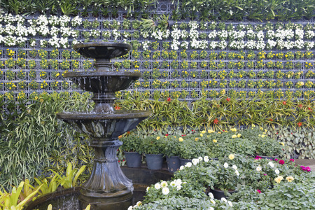 Three-story cascading fountain with flowers in the background.の写真素材