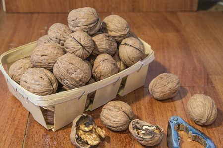 Walnuts in wicker basket with wooden background and nutcrackersの写真素材