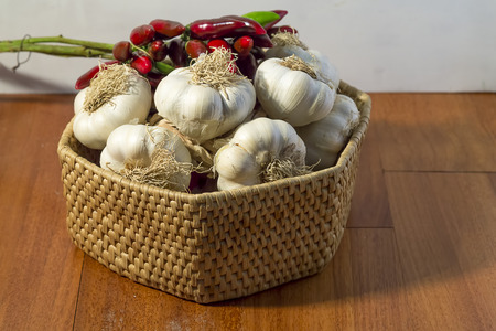 basket of garlic and red pepper on a wooden blackgroundの写真素材