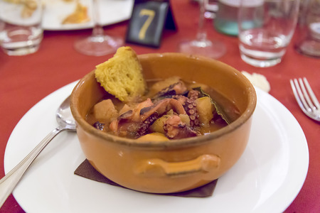 octopus soup with ground potatoes and with spoon and white dishの写真素材