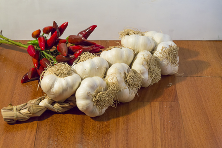 garlic braid and red pepper on a wooden blackgroundの写真素材