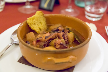 octopus soup with ground potatoes and spoon and white dishの写真素材