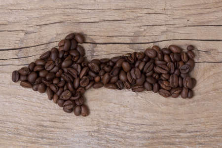 Arrow of coffee beans pointing to some direction, set on an old wooden board, horizontal layoutの写真素材