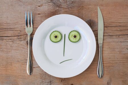 Vegetable Face on Plate with knife and fork, set on wooden board - Male, Shockedの写真素材