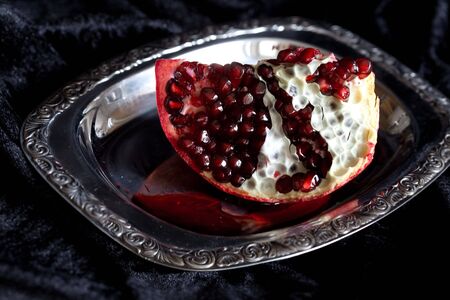 Sliced Pomegranate with arils on silver plate with reflexionの写真素材
