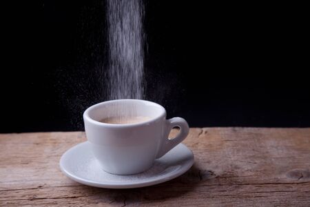 Coffee with sugar pouring down on wooden tableの写真素材