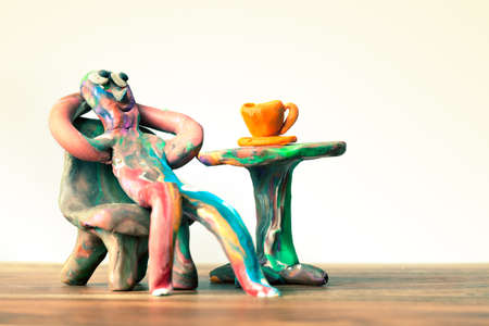 Miniature clay man sitting in cafe with cup of coffee and relaxingの写真素材