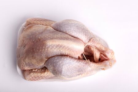 Raw whole plucked chicken ready for cooking on a plastic styrofoam disposable punnetの写真素材