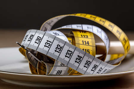 Fork with measuring tape as a symbol of disciplined dieting and weight reductionの写真素材