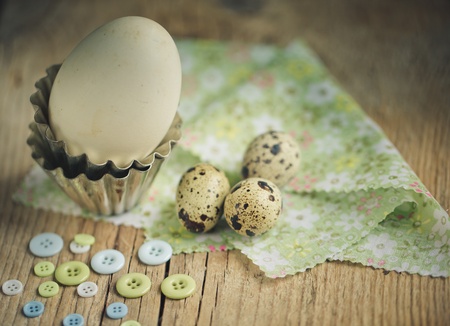 Different Eggs from Quail and Duck on table with Buttons and with small metal baking form