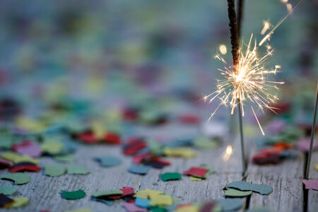 Burning Sparklers with colorful Confetti on wooden Table at a Partyの写真素材