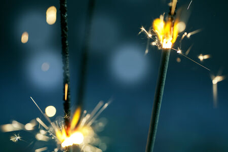 Sparklers burning in the dark at night with bright sparks and flameの写真素材