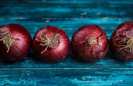 Whole Red Onions on Cyan Blue Wooden Boardの写真素材