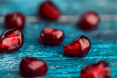 Fresh bright red Pomegranate Grenadine seeds on blue wooden backgroundの写真素材