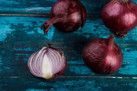 Whole Red Onions on Cyan Blue Wooden Boardの写真素材