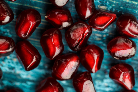 Fresh bright red Pomegranate Grenadine seeds on blue wooden backgroundの写真素材