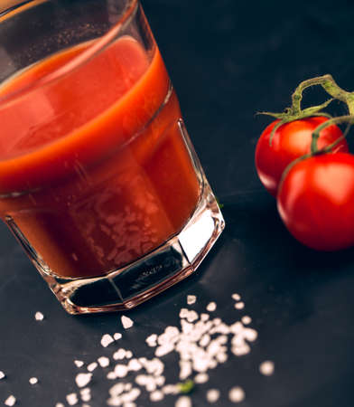 Tomato Juice and fresh tomatoes on black slate with coarse saltの写真素材