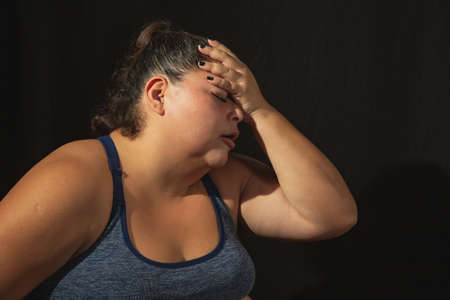 Overweight woman in sportswear on black backgroundの写真素材