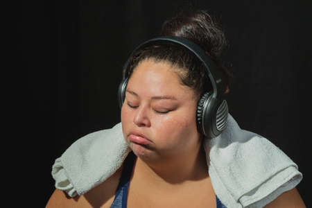 Overweight woman in sportswear on black background