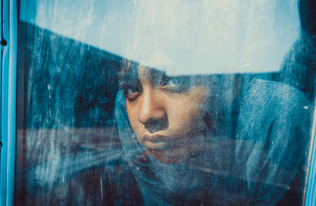 child looks through old glass window