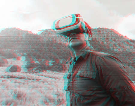 a man in VR glasses receiving new experience in mountainの写真素材