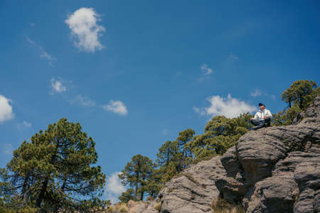 Sportsman practicing Yoga on stone edge above landscape