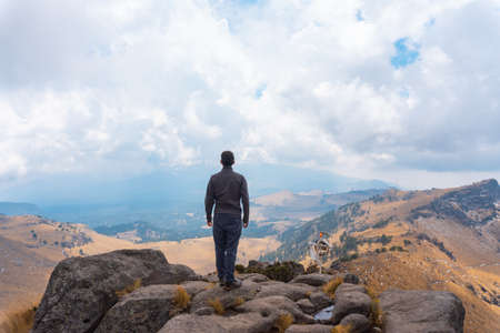 Man standing on a ledge of a mountain, enjoying the beautiful viewの写真素材