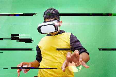 a boy using virtual reality simulator headset on green background