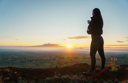 woman traveler drinks coffee with a view of the mountain landscapeの写真素材