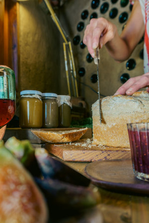 womans hand cutting bread to spread jam