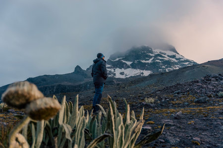 Young man standing on top of stone and enjoying amazing volcanic mountainの写真素材