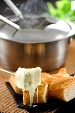 Dipping into a cheese fondueの写真素材