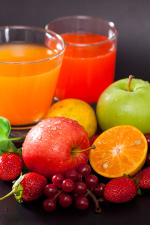 Mixed juices and fruits on black background.の写真素材