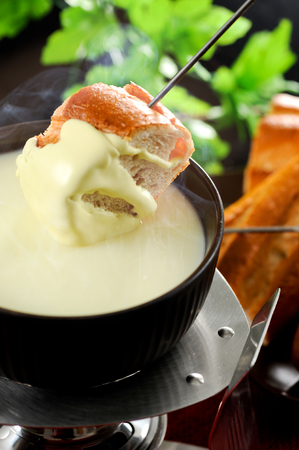 Dipping into a cheese fondueの写真素材