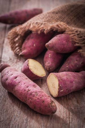 Raw sweet potatoes on wood backgroundの写真素材