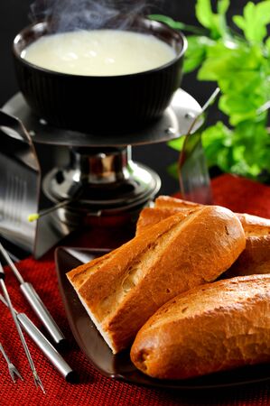 Dipping into a cheese fondueの写真素材