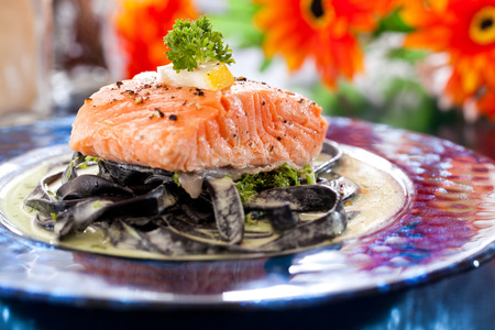 Black fettucine pasta with white sauce and salmonの写真素材