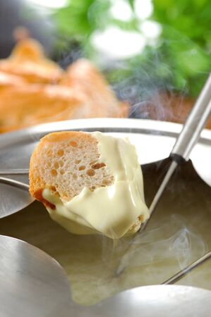 Dipping into a cheese fondueの写真素材