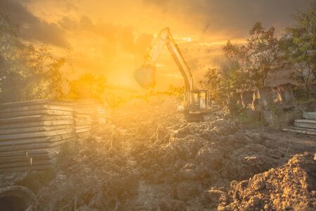 Backhoe with raised bucket at sunsetの写真素材