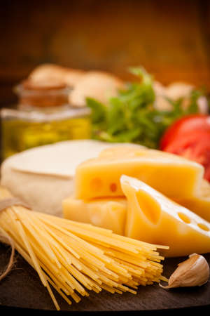 Cheese and pasta with ingredients on wood backgroundの写真素材
