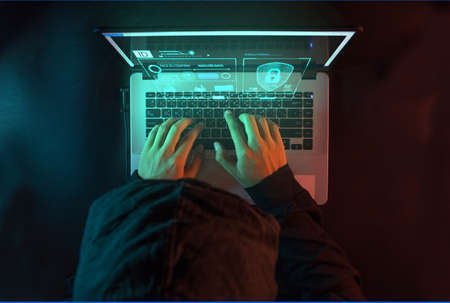 Overhead hacker in the hood working with futuristic laptopの写真素材