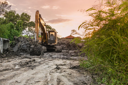 Backhoe with raised bucket at sunsetの写真素材
