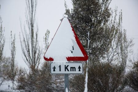 Road sign covered with snow in winter during the snawfallの写真素材