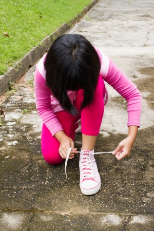 Asian girl tying shoes ropeの写真素材