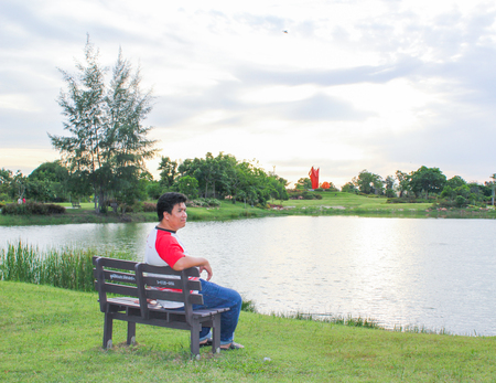 Asian man sitting on wood bench in the parkの写真素材