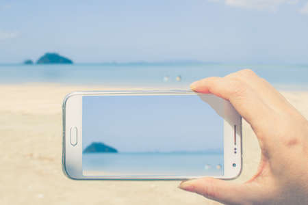 someone taking photo with smartphone at the beachの写真素材