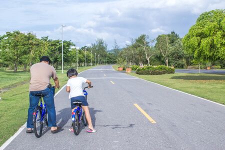 father teach his daughter to ride a bicycleの写真素材